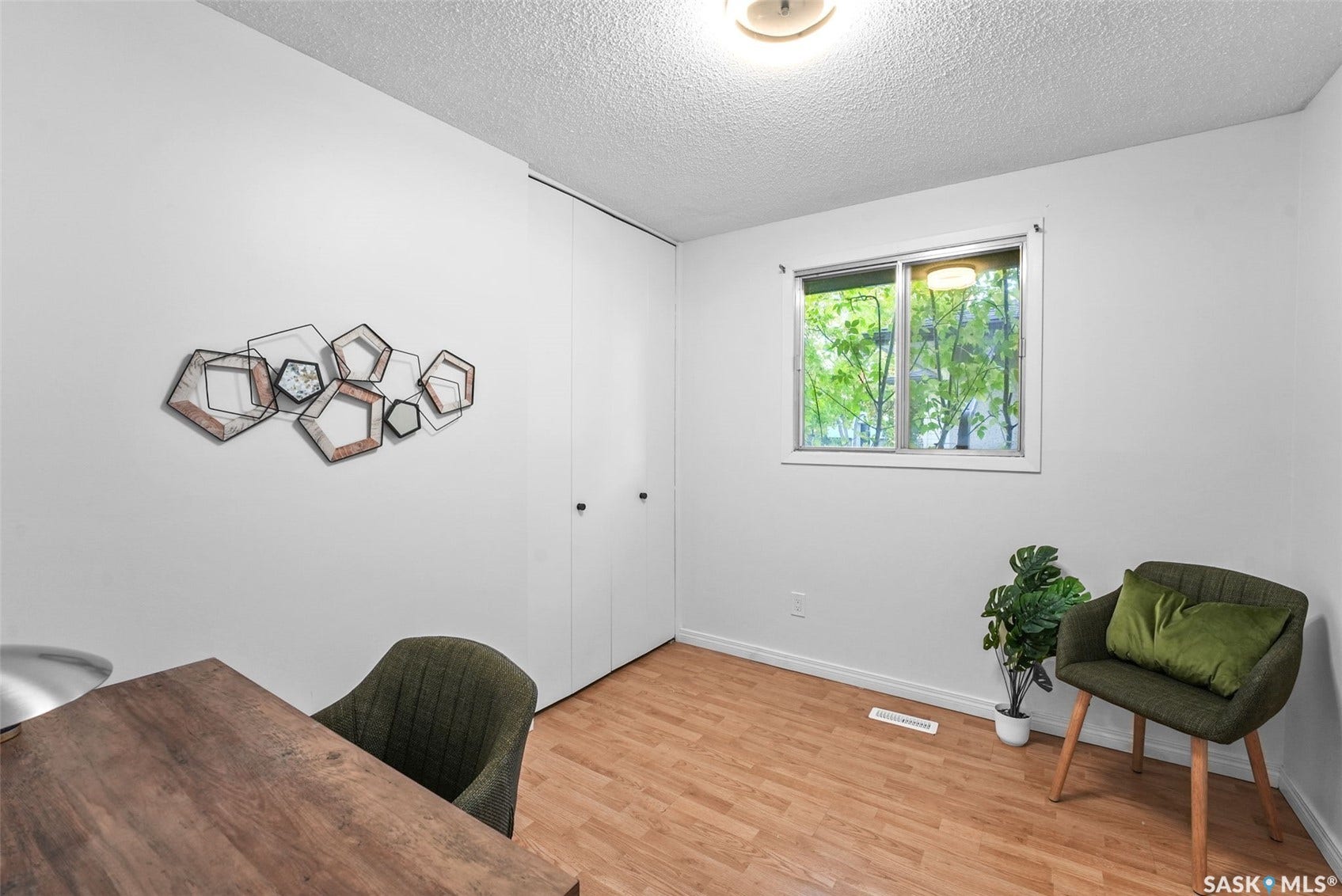 Wood-finish flooring, built-in storage with bi-fold doors, and a window with a white trim