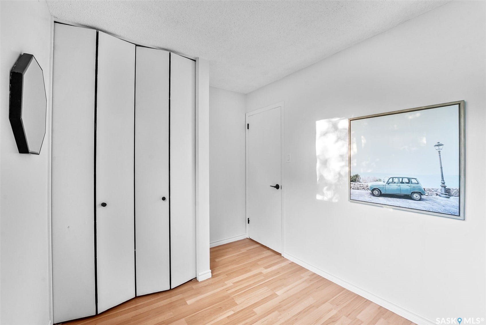 Wood-finish flooring with white walls and a bi-fold closet