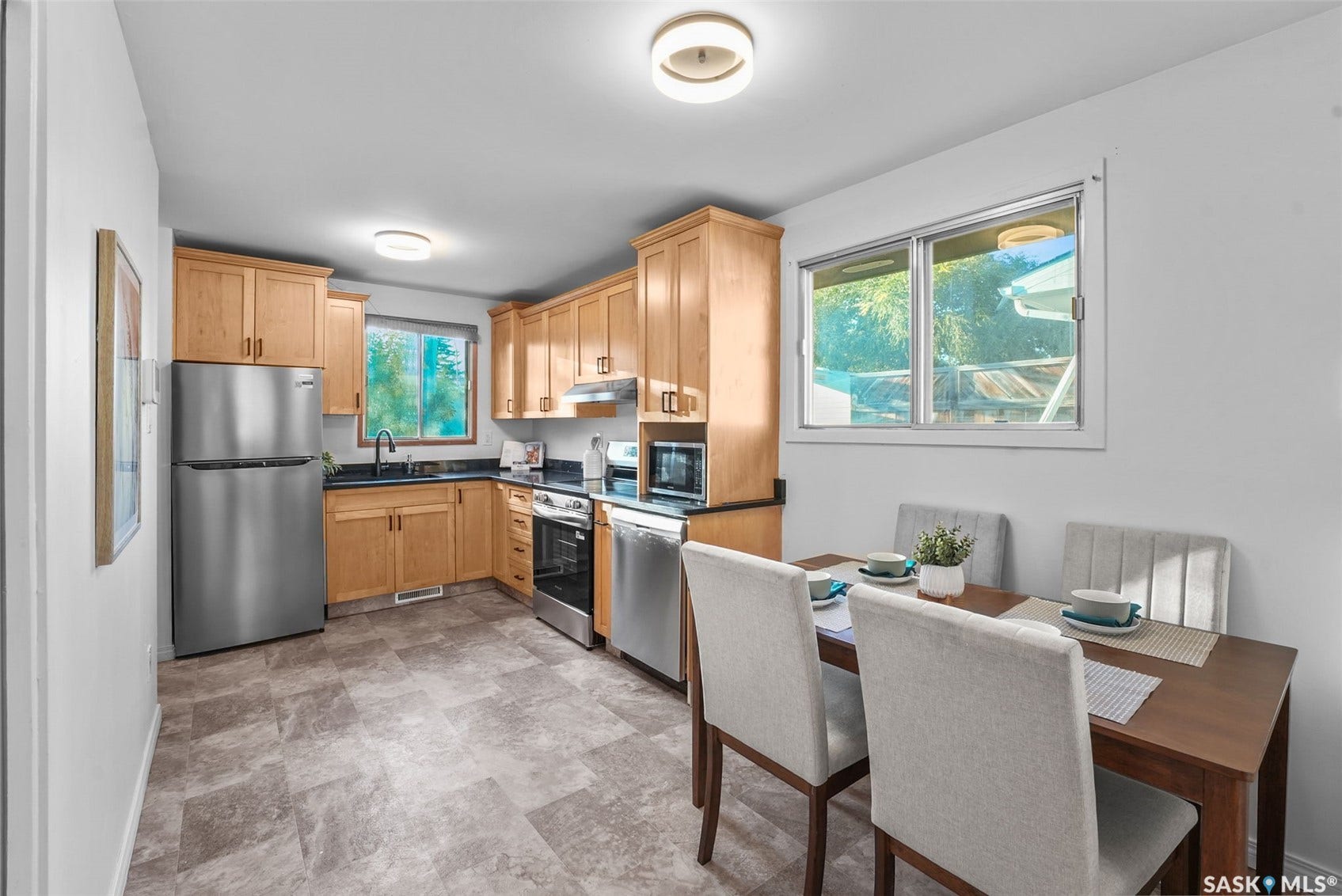 Bright and efficient kitchen featuring warm wood cabinetry, stainless steel appliances, and a tile work surface