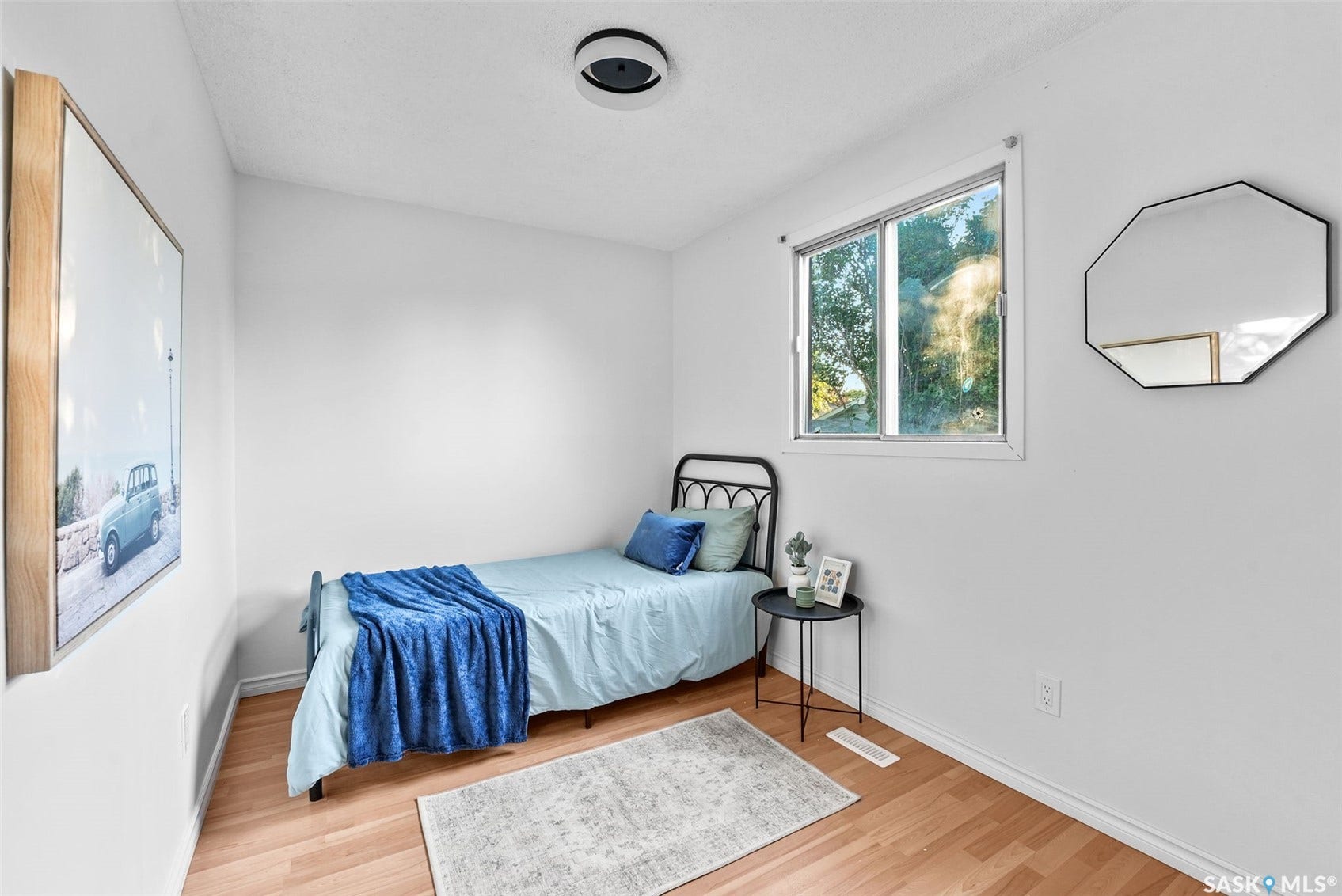 Room featuring wood-finish flooring, a window with exterior visibility, and white walls