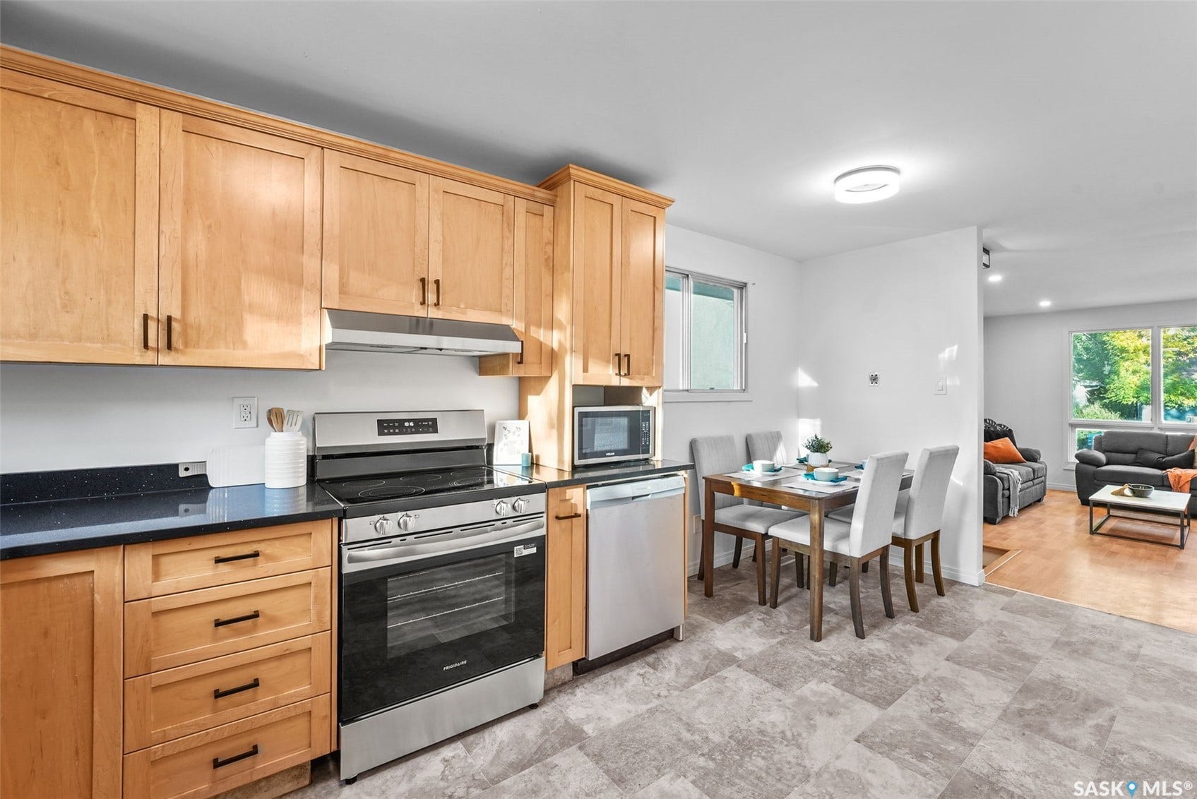 Kitchen featuring wood cabinetry, dark countertops, stainless steel appliances, and tile flooring