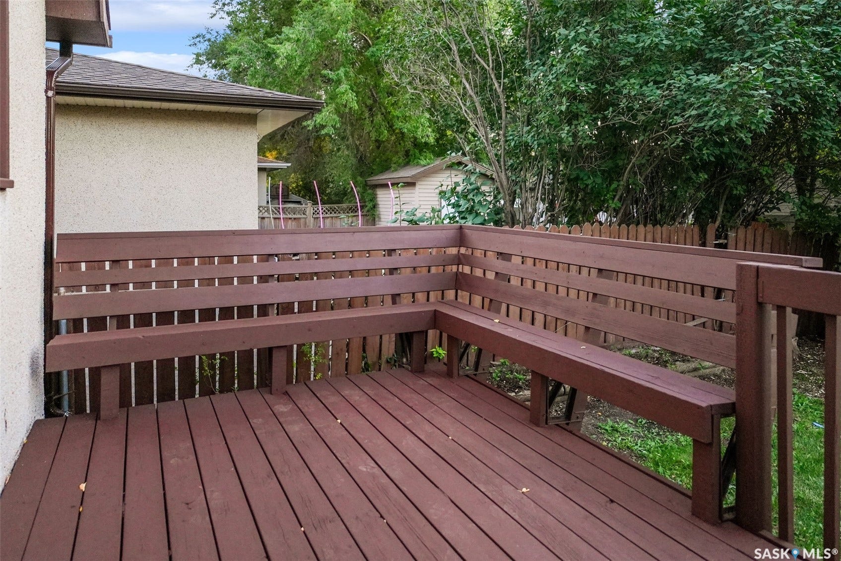 Spacious outdoor deck featuring integrated wooden bench seating and a wooden privacy fence