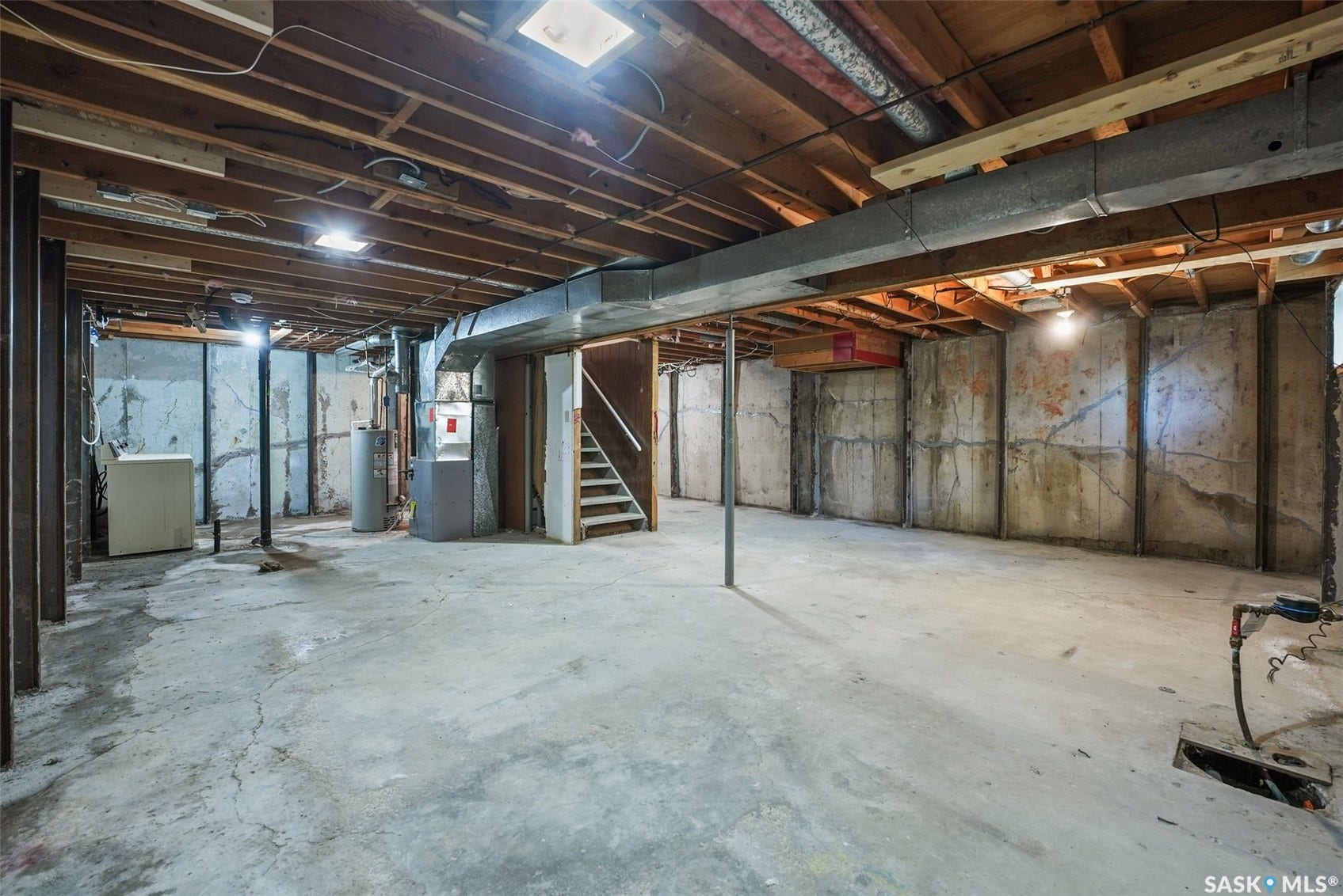 Spacious unfinished basement with exposed wood joists and concrete flooring