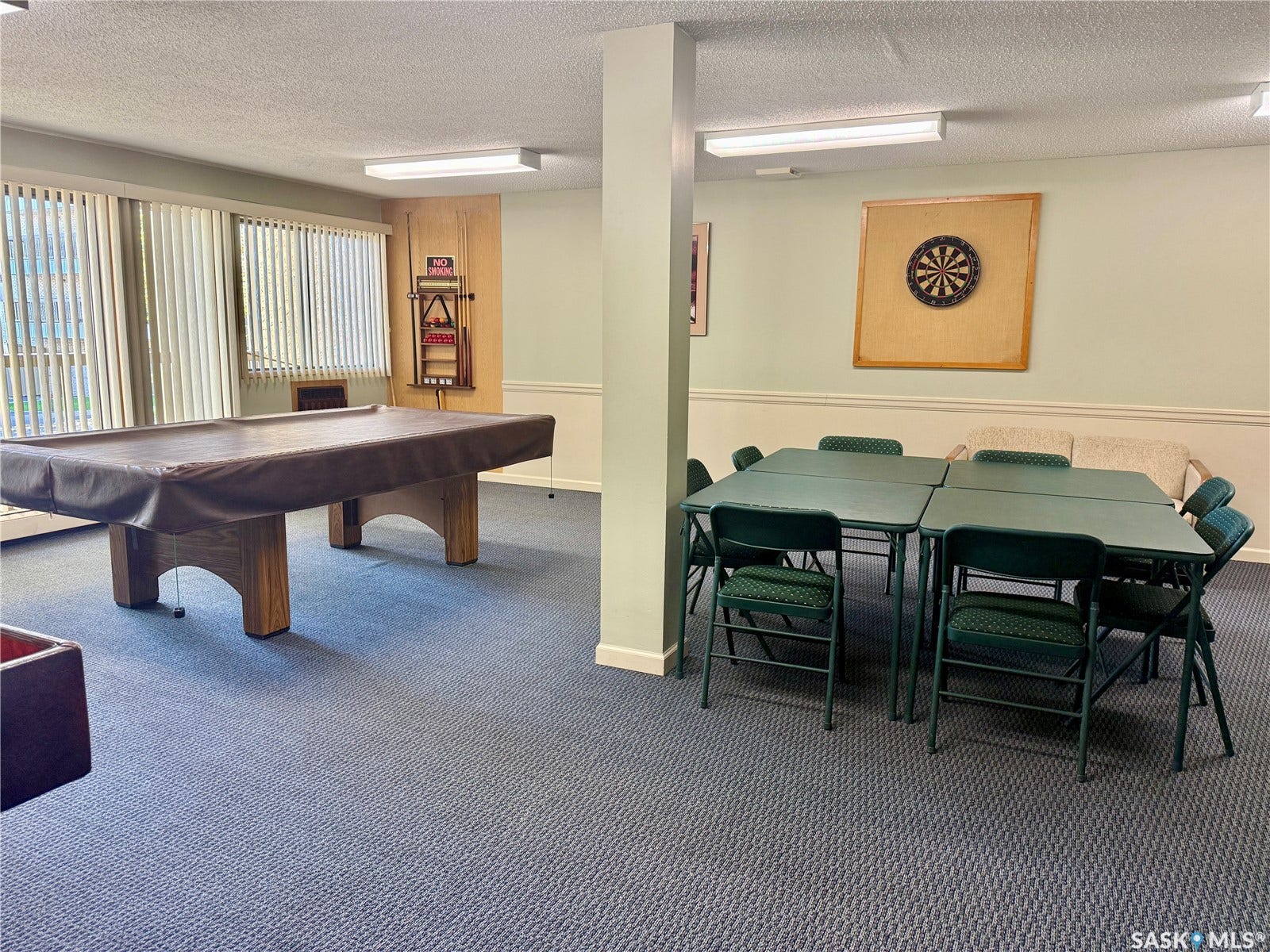 Recreational room featuring a pool table, multiple folding tables with chairs, and a dartboard