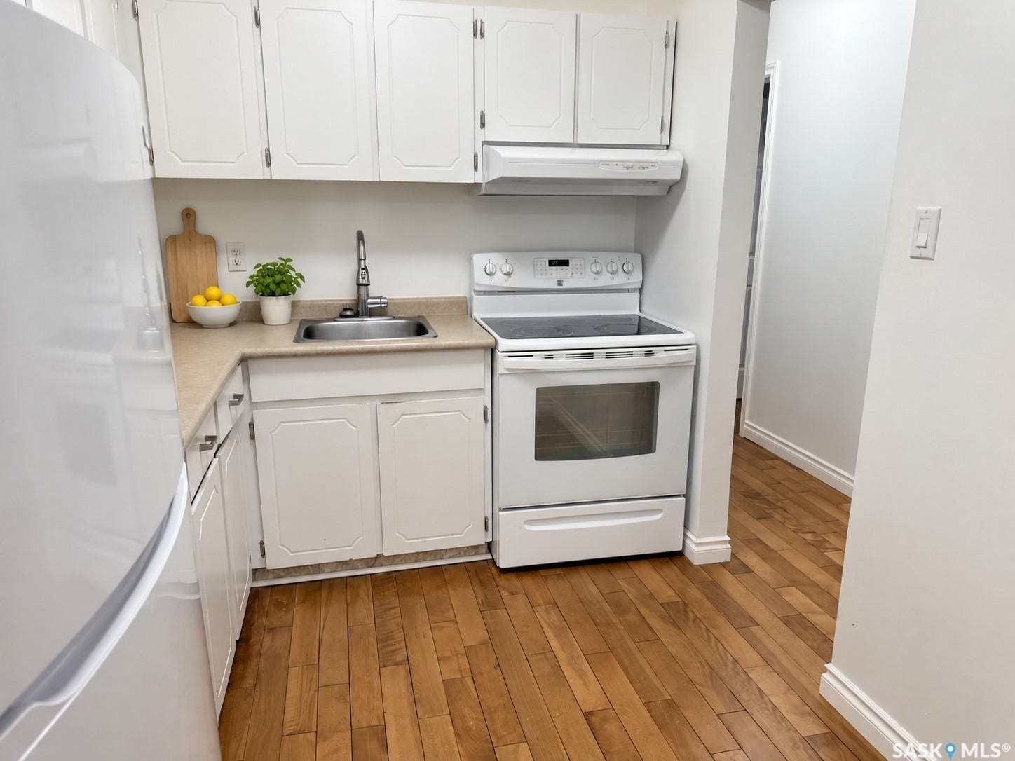 Kitchen featuring wood-finish flooring, white cabinetry, a stainless steel sink, and a white electric range