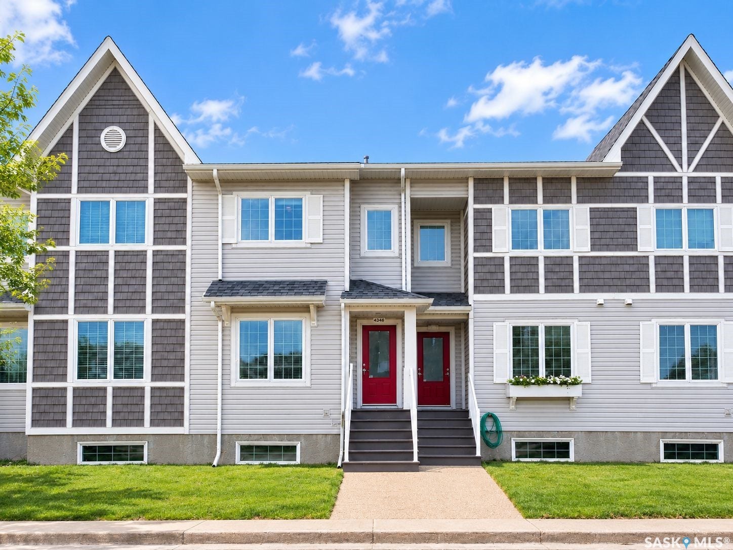 Siding exterior with decorative shingles, multiple windows, and two red entry doors