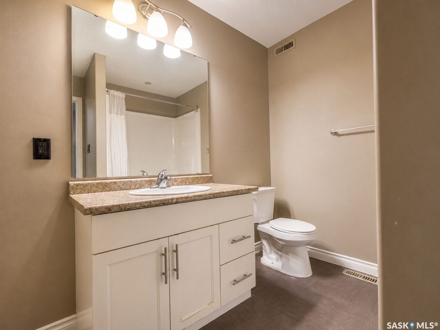 White vanity with brushed nickel hardware, integrated sink, and a speckled countertop