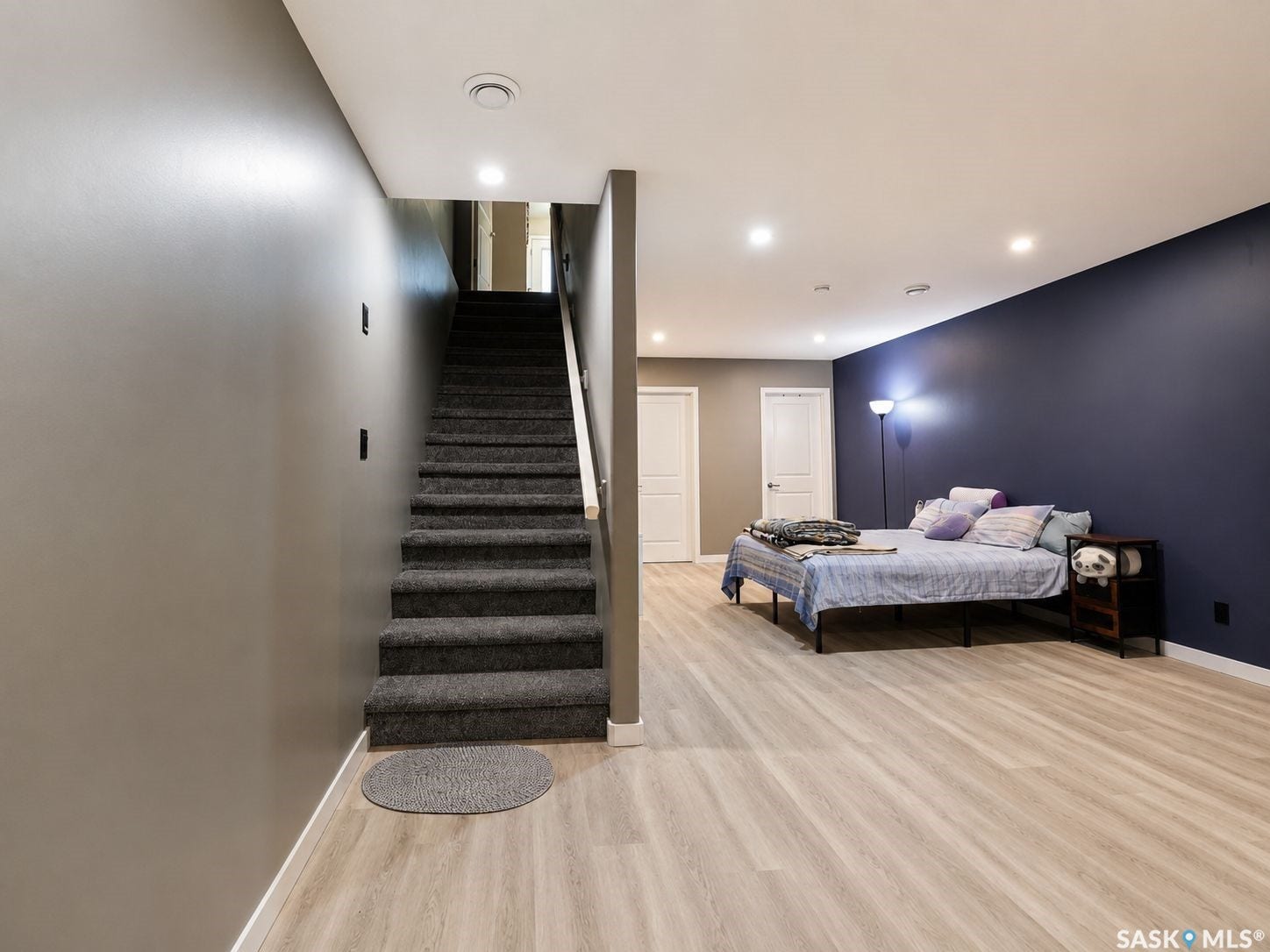 Carpeted staircase with white handrail, recessed lighting, and wood-finish flooring