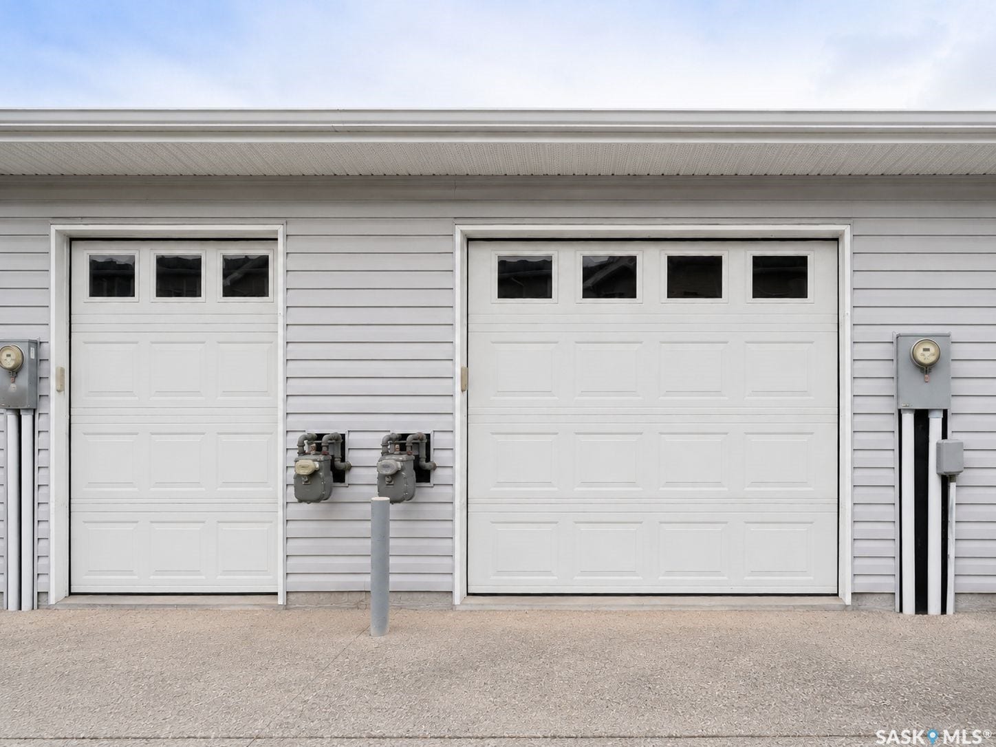 White panel garage doors with upper square window accents and gray horizontal siding