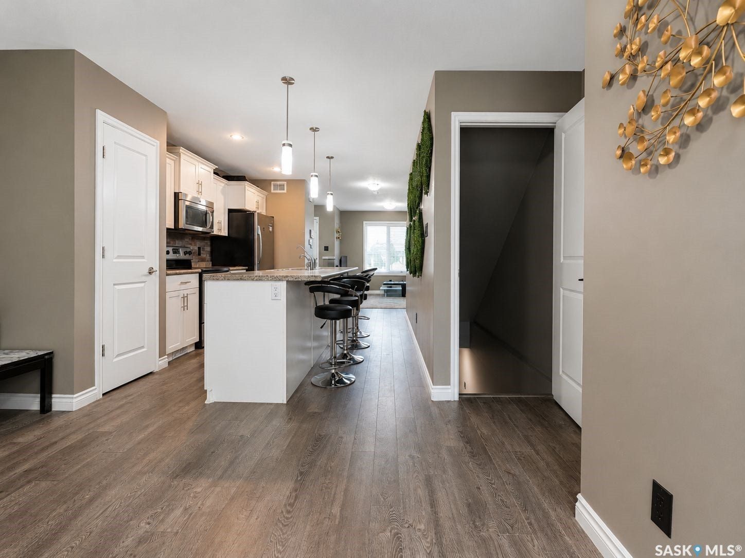 Kitchen featuring white cabinetry, stone countertops, stainless steel appliances, and a breakfast bar with pendant lighting