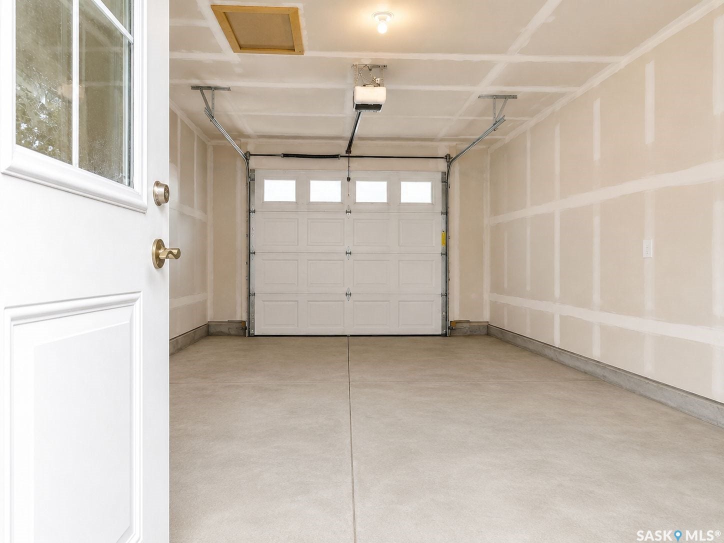 Attached single-car garage with a paneled door, transom windows, and concrete flooring