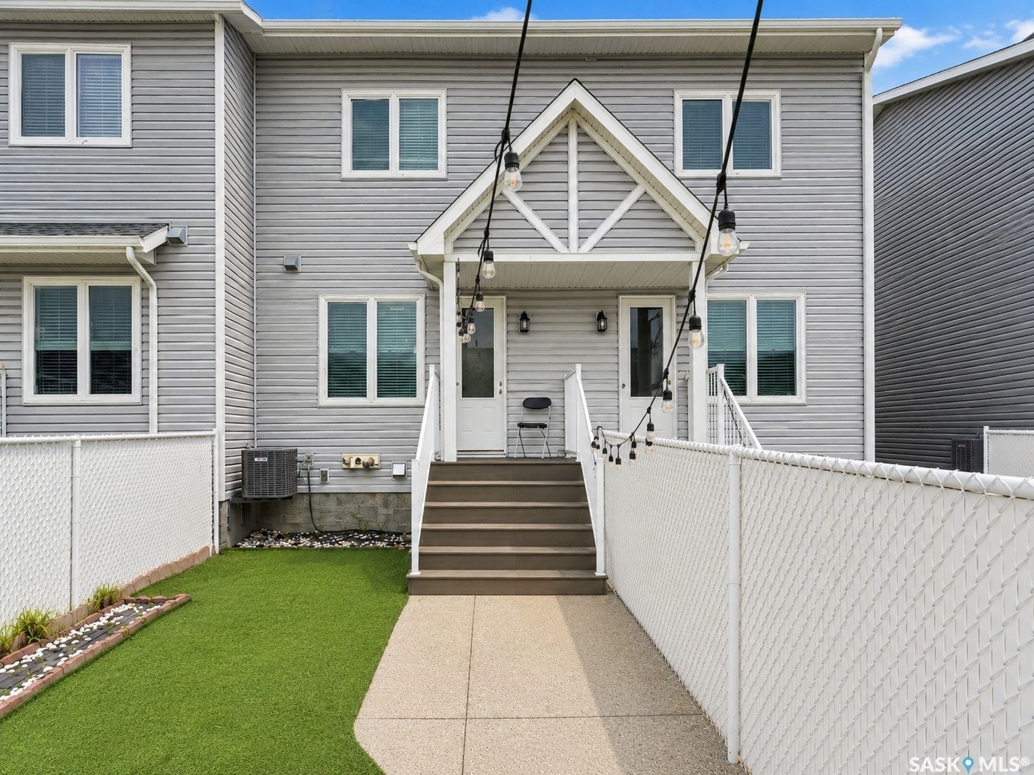 Gray siding exterior with multiple windows, a covered entryway, and concrete stairs