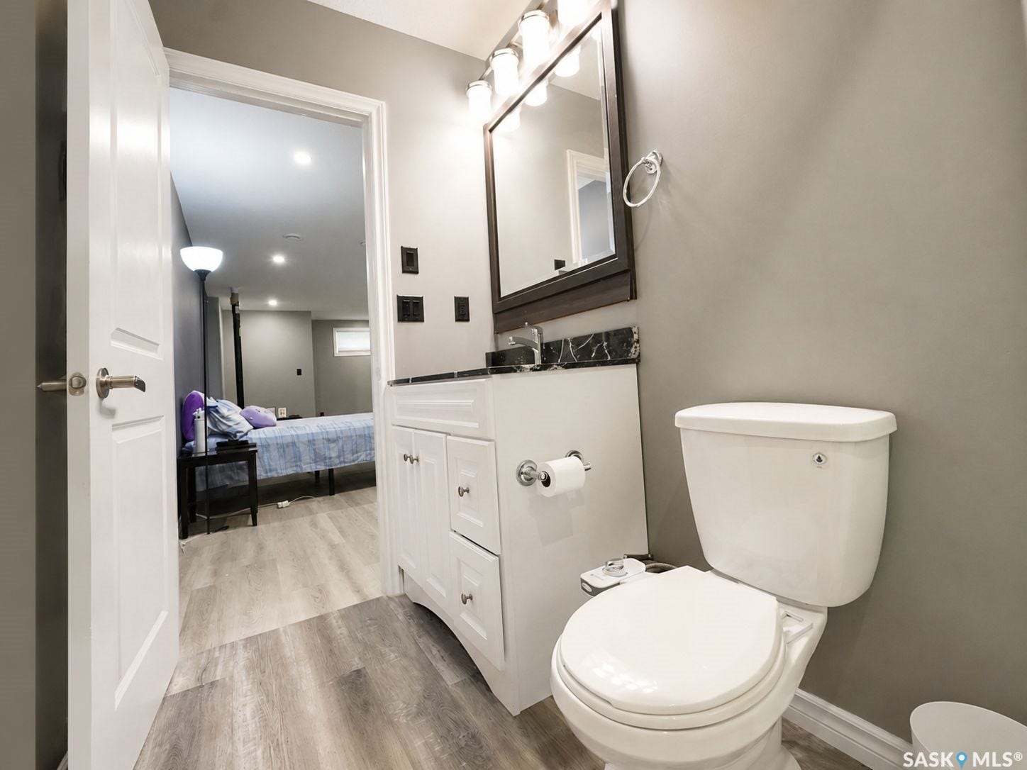 White vanity with a dark countertop and rectangular mirror