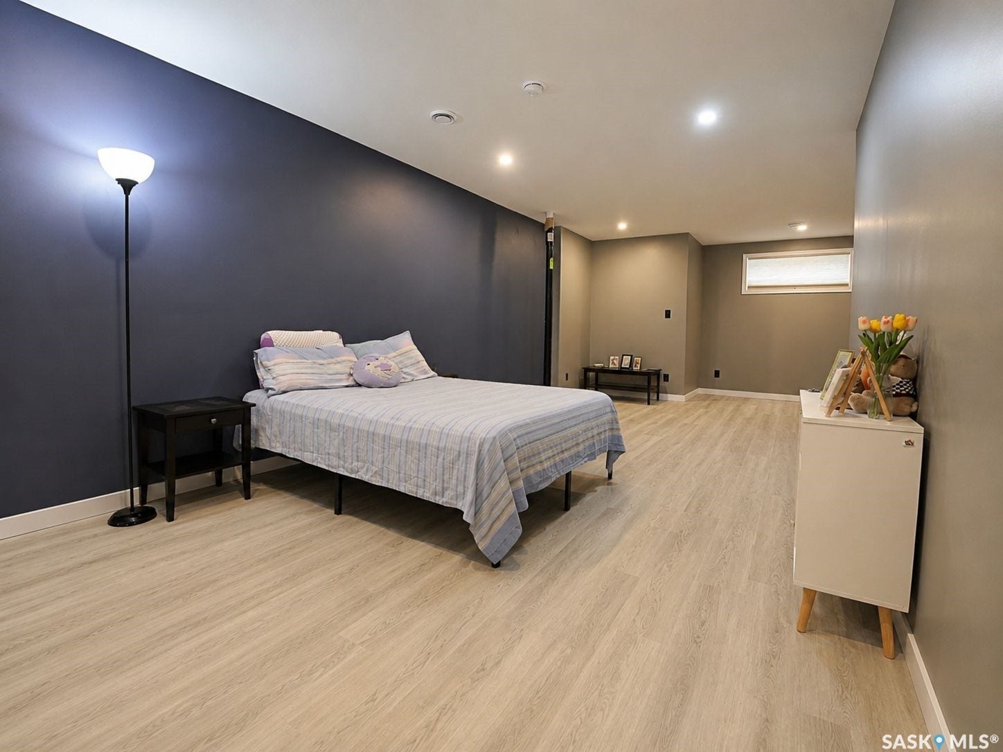 Spacious room featuring light wood-finish flooring, recessed lighting, and a window with a privacy blind