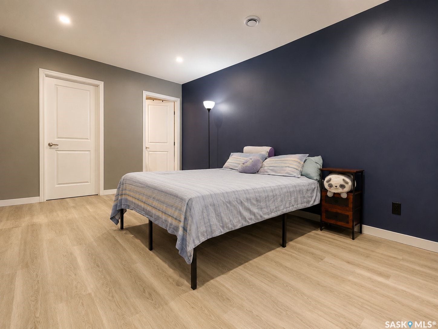 Recessed ceiling lighting, wood-finish flooring, white interior doors, and a contrasting accent wall