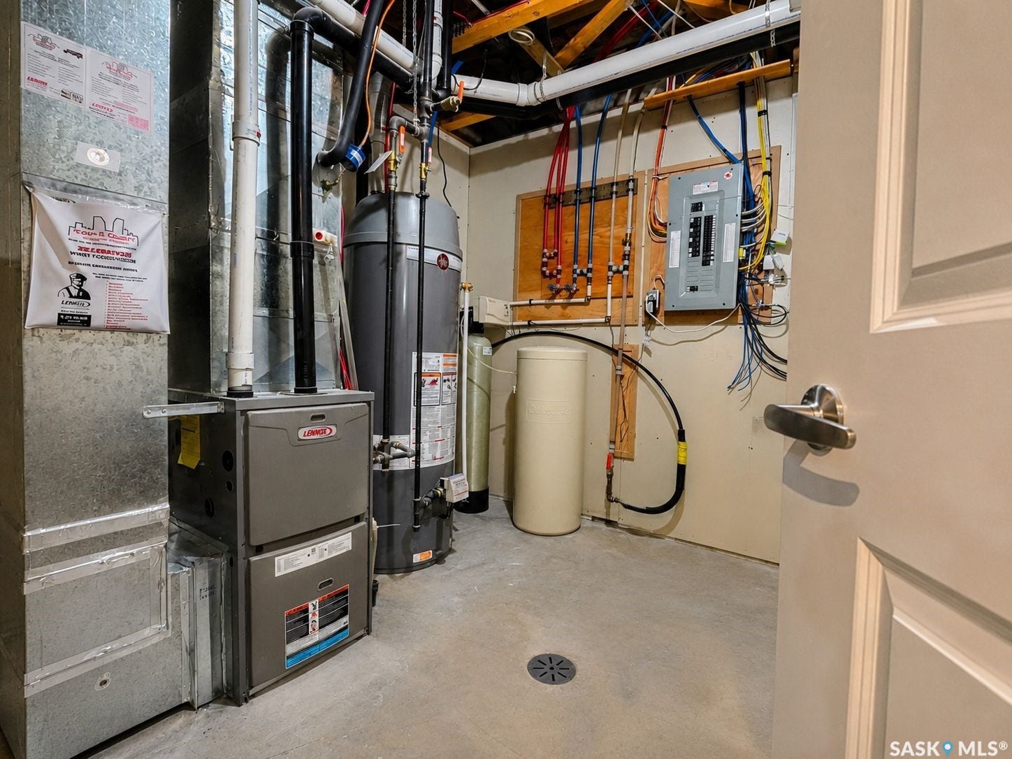 Concrete flooring with a floor drain, furnace, water heater, water softener, and electrical panel