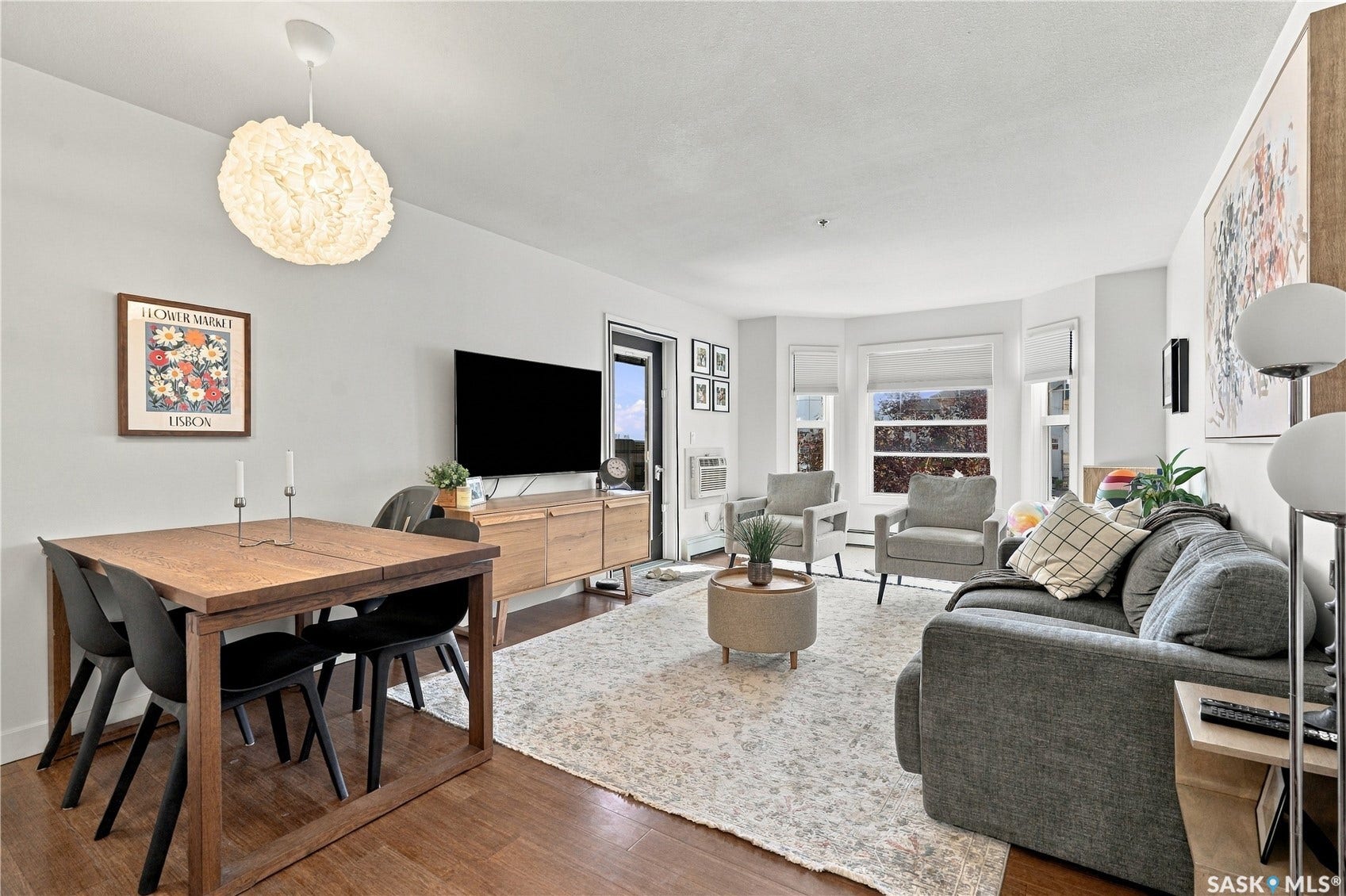 Wood-finish flooring throughout, white walls, bay window with multiple panes, light fixture, and built-in wall unit