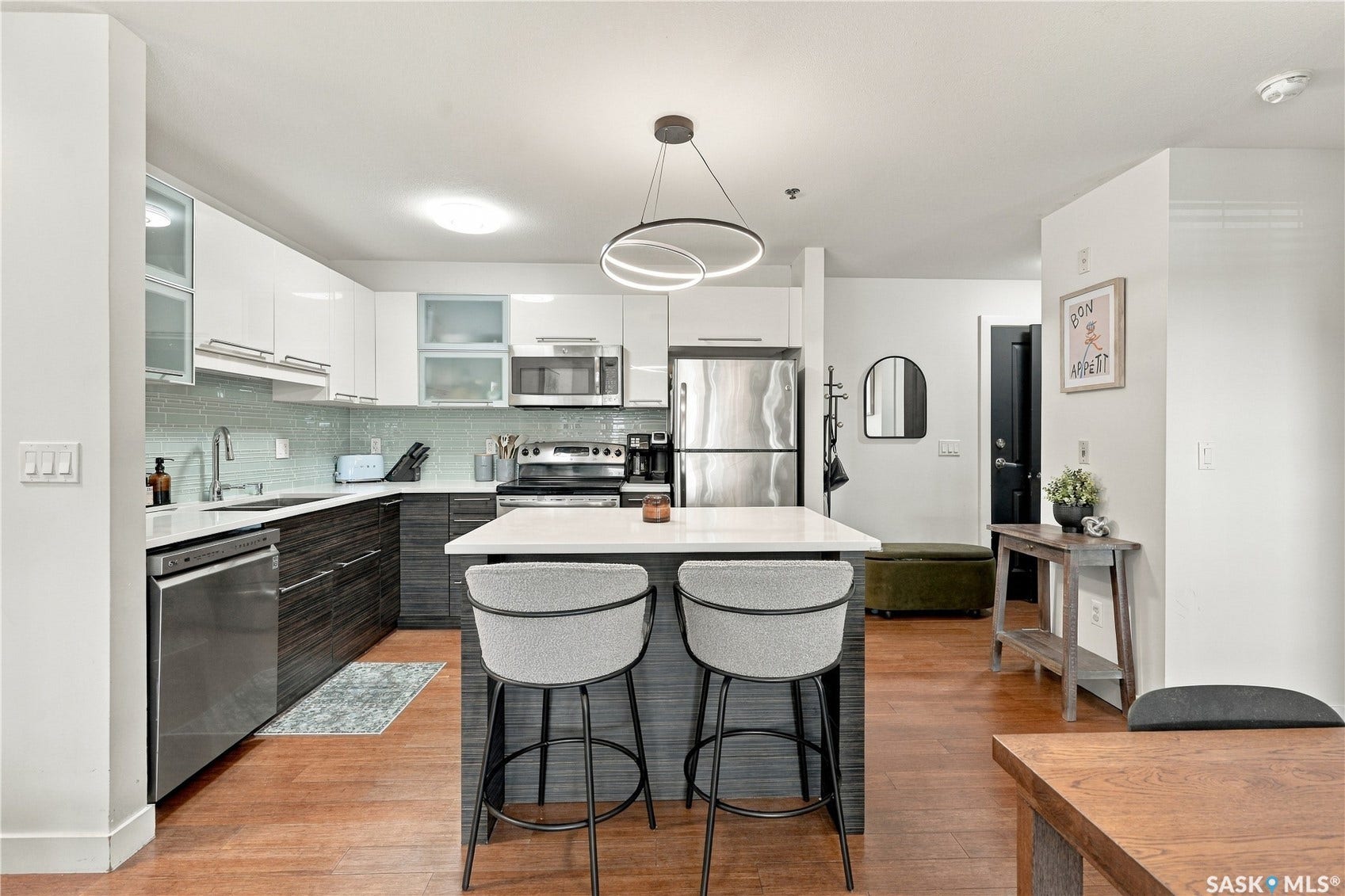 Kitchen featuring wood-finish flooring, white upper cabinetry, two-tone lower cabinetry, and a center island with countertop seating