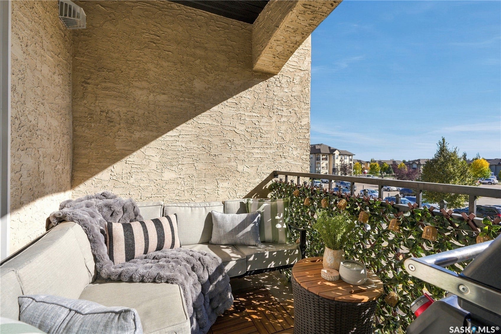 Balcony featuring a textured stucco wall, dark metal railing, and wood-finish flooring