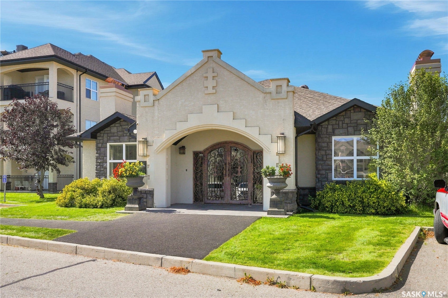 Stucco and stone exterior with arched entry and decorative iron doors