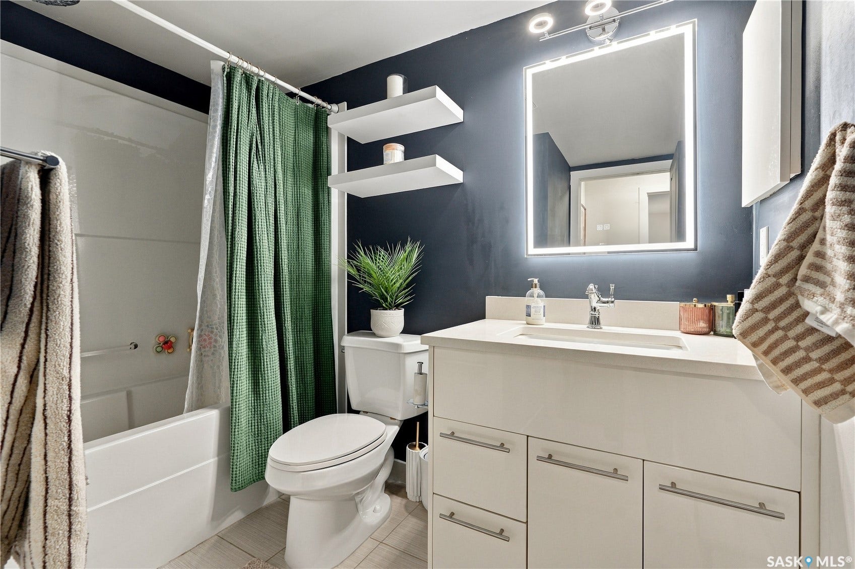 Modern vanity with an integrated sink and brushed nickel hardware, complemented by an illuminated mirror