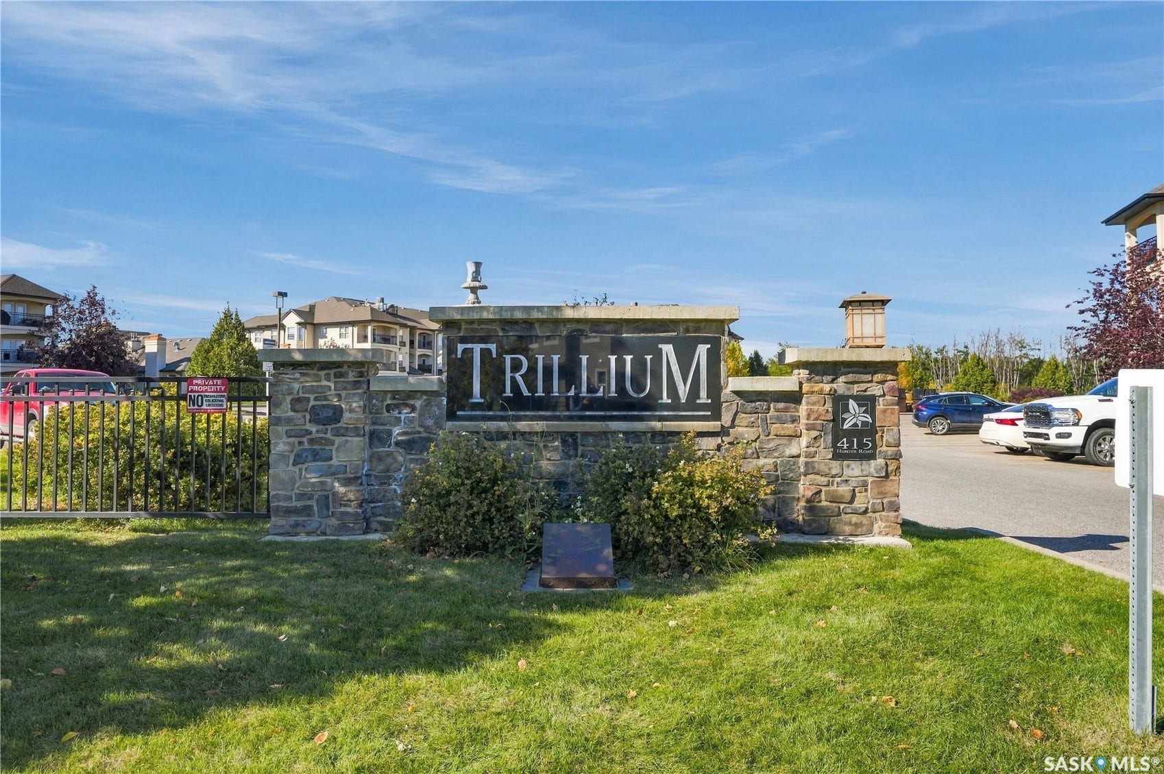 Stone-clad monument signage with integrated lighting features a metal fence