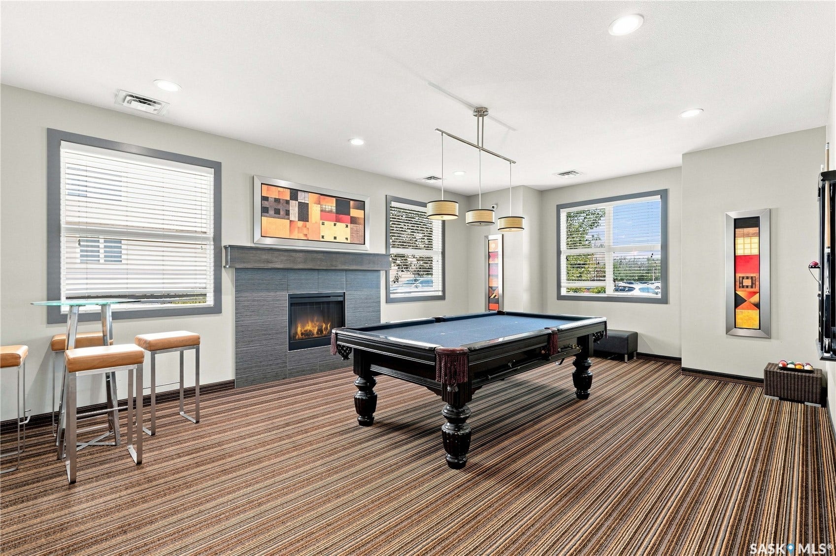 Room featuring a stone-clad fireplace, striped carpet, and recessed lighting