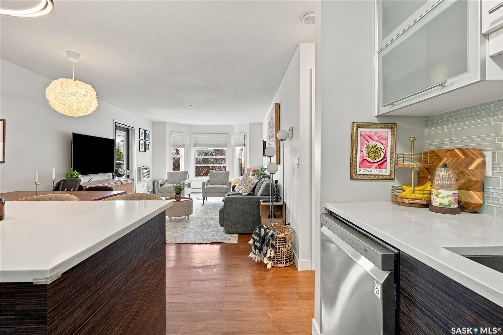 Kitchen island with a light-toned countertop, integrated sink, and dishwasher, offering an open concept to the living space