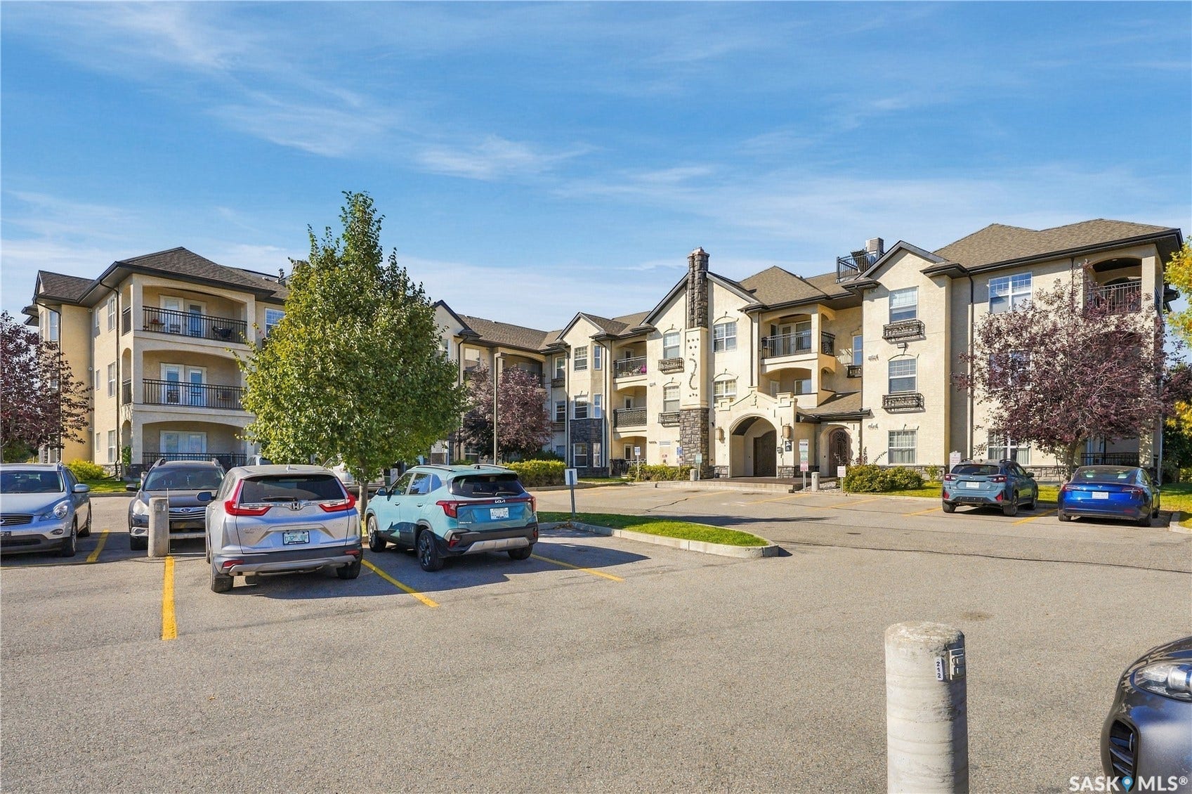 Exterior featuring multiple balconies, stone accents, and a paved parking area