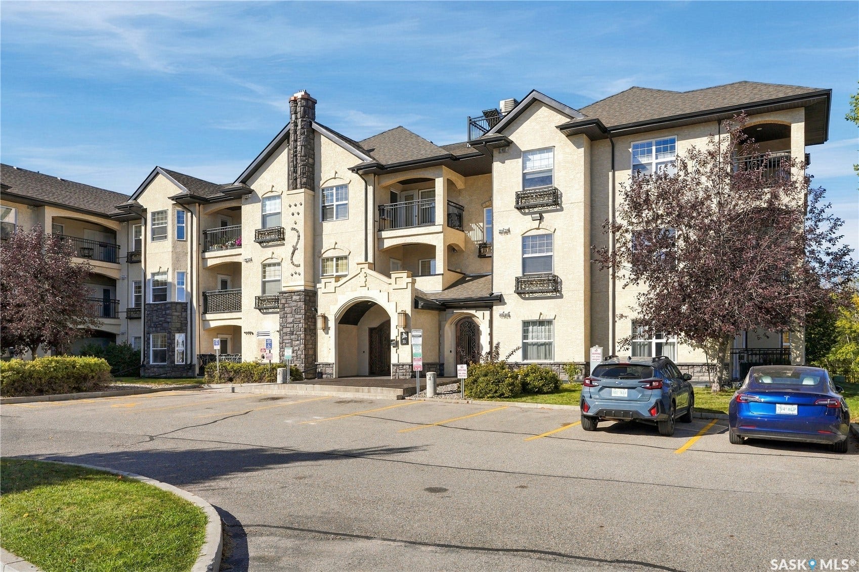 Multi-story stucco exterior with stone accents and a prominent archway entry