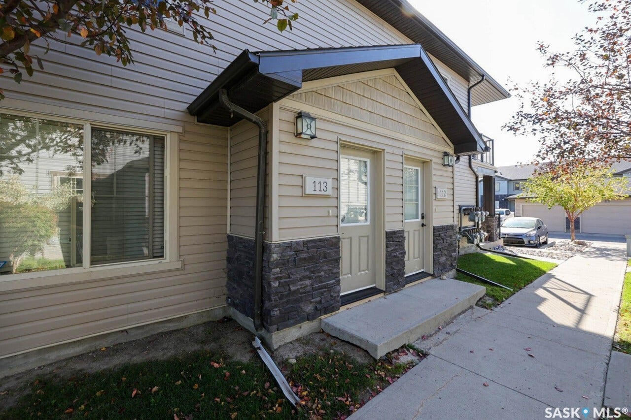 Siding exterior with stone veneer accents, covered entry, and concrete walkway