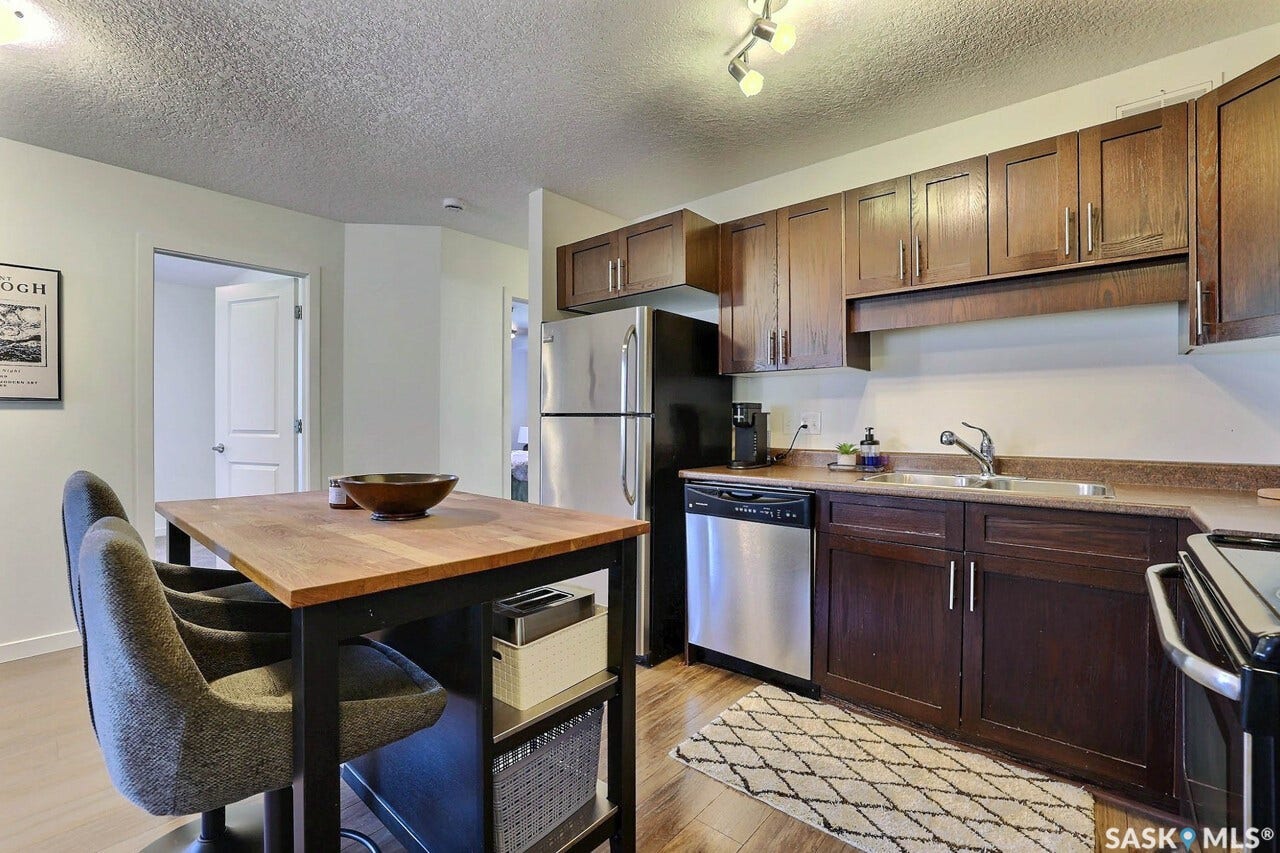 Kitchen featuring wood-finish flooring, dark wood cabinetry, stainless steel appliances, and track lighting