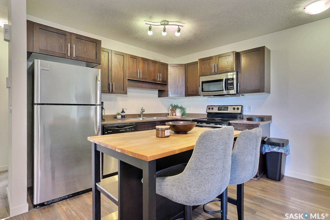 Kitchen featuring stainless steel appliances, wood-finish cabinetry, a built-in microwave, wood-finish flooring, and a kitchen island with a butcher block countertop