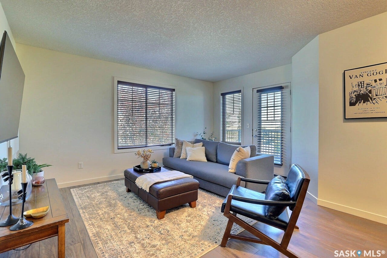 Spacious living area featuring wood-finish flooring and ample natural light from multiple windows