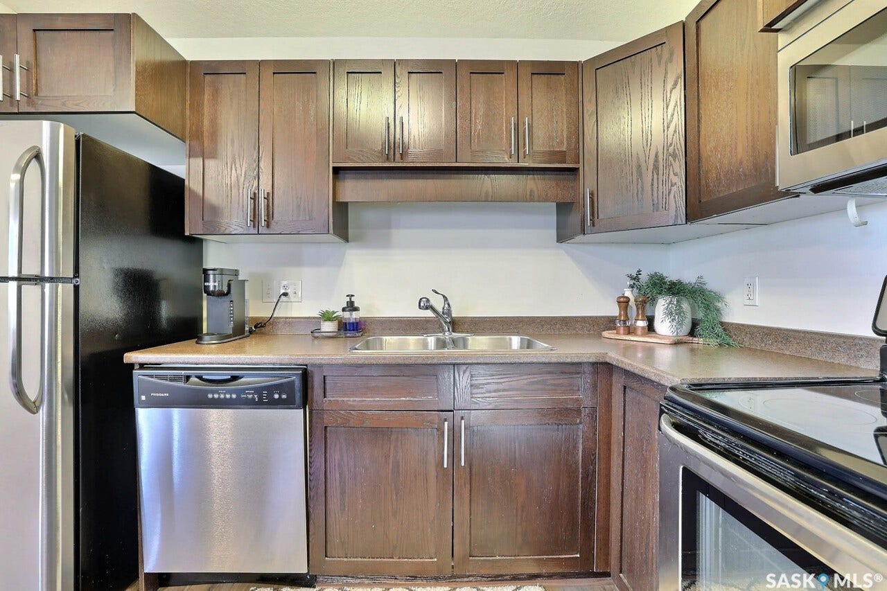 Dark wood-finish cabinetry with silver hardware, stainless steel dishwasher, double basin sink, and built-in microwave