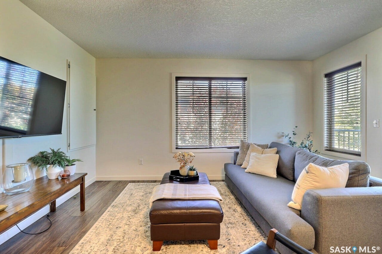 Wood-finish flooring, multiple windows with blinds, and neutral wall tones