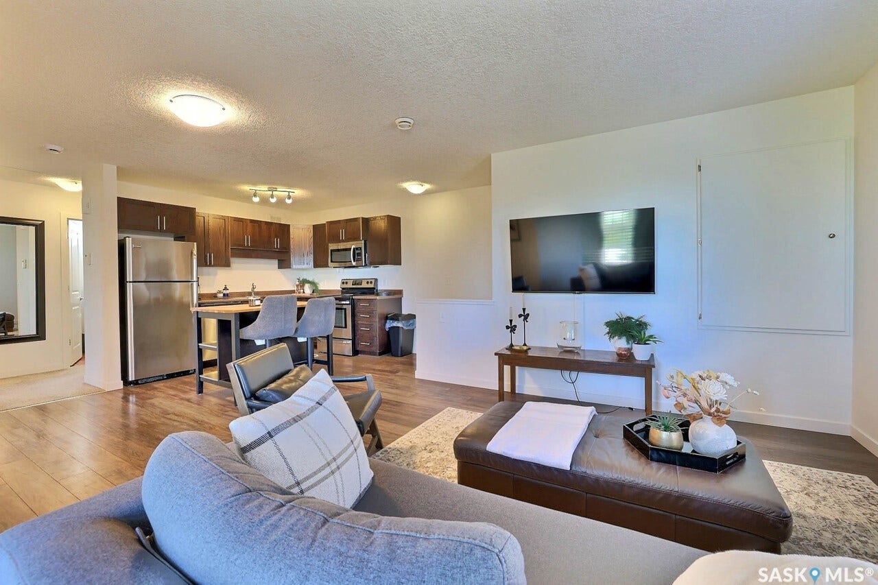 Open-concept living area featuring wood-finish flooring, recessed lighting, and a kitchen with dark cabinetry and stainless steel appliances