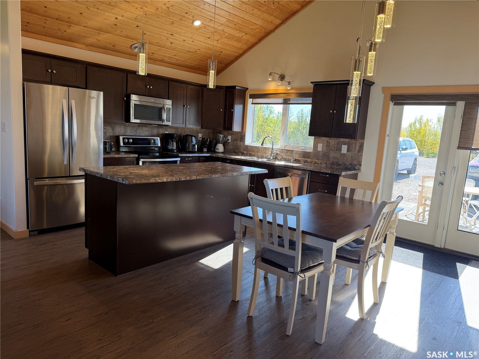Kitchen featuring stainless steel appliances, dark wood-finish cabinetry, a central island with countertop, and wood-finish flooring
