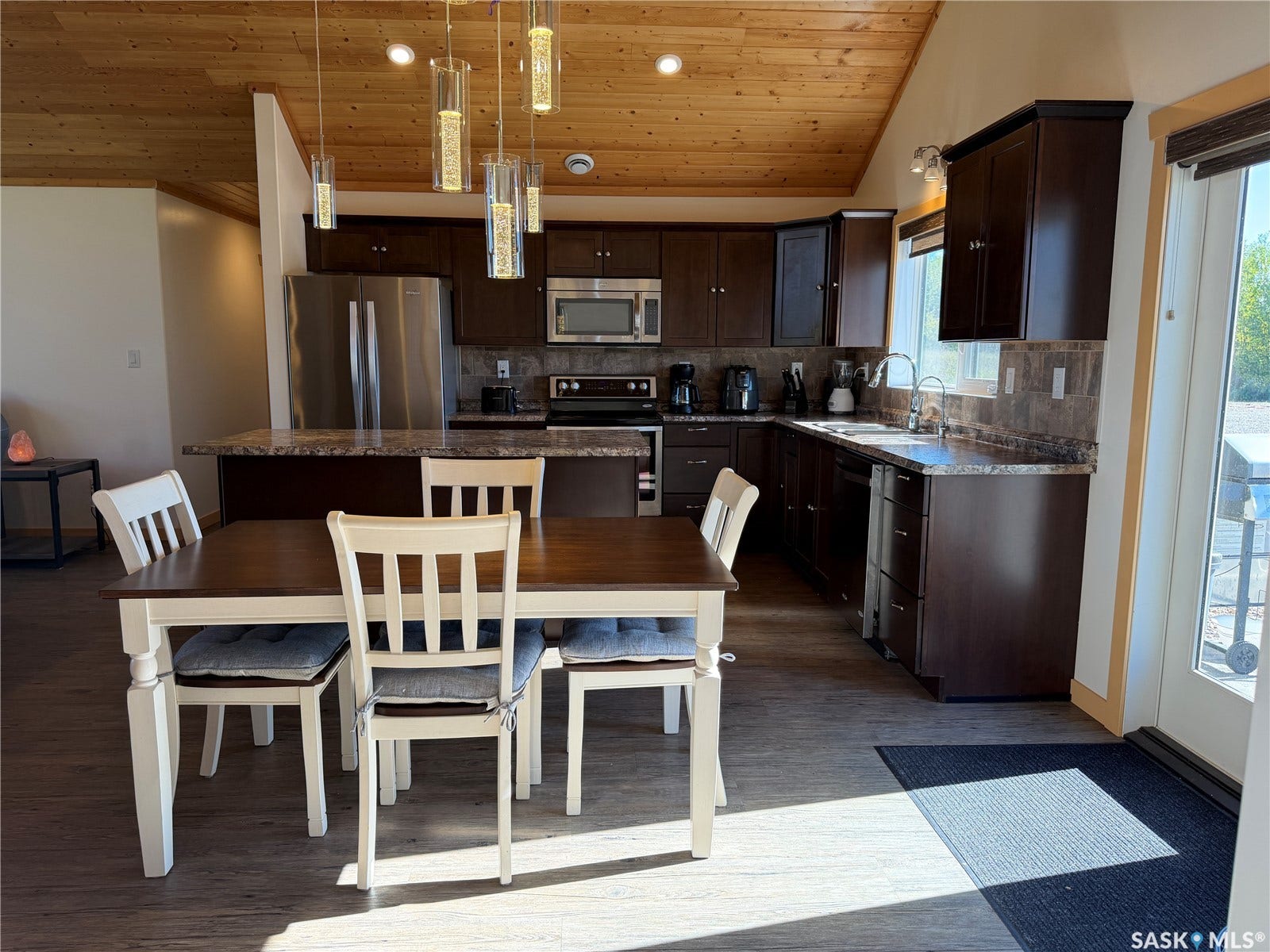 Kitchen featuring dark wood cabinetry, stainless steel appliances, a breakfast bar, and wood-finish flooring