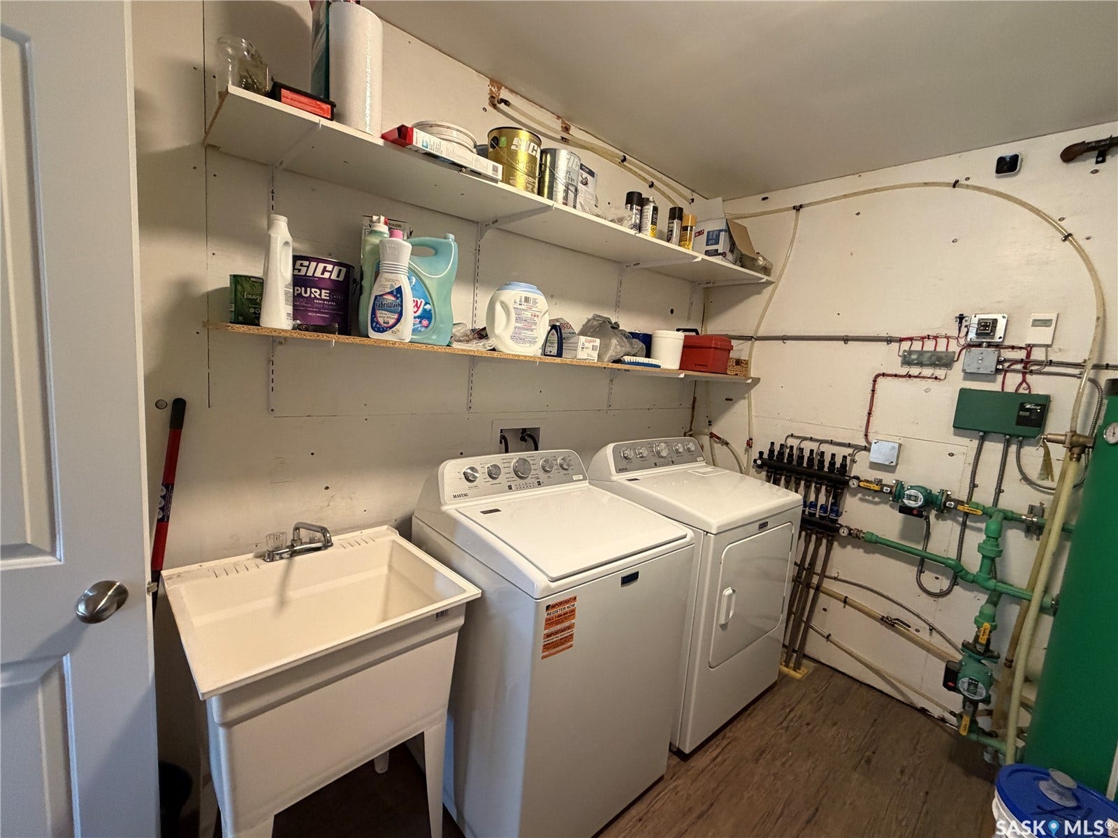 Laundry area featuring a utility sink, two appliances, and wall-mounted shelving