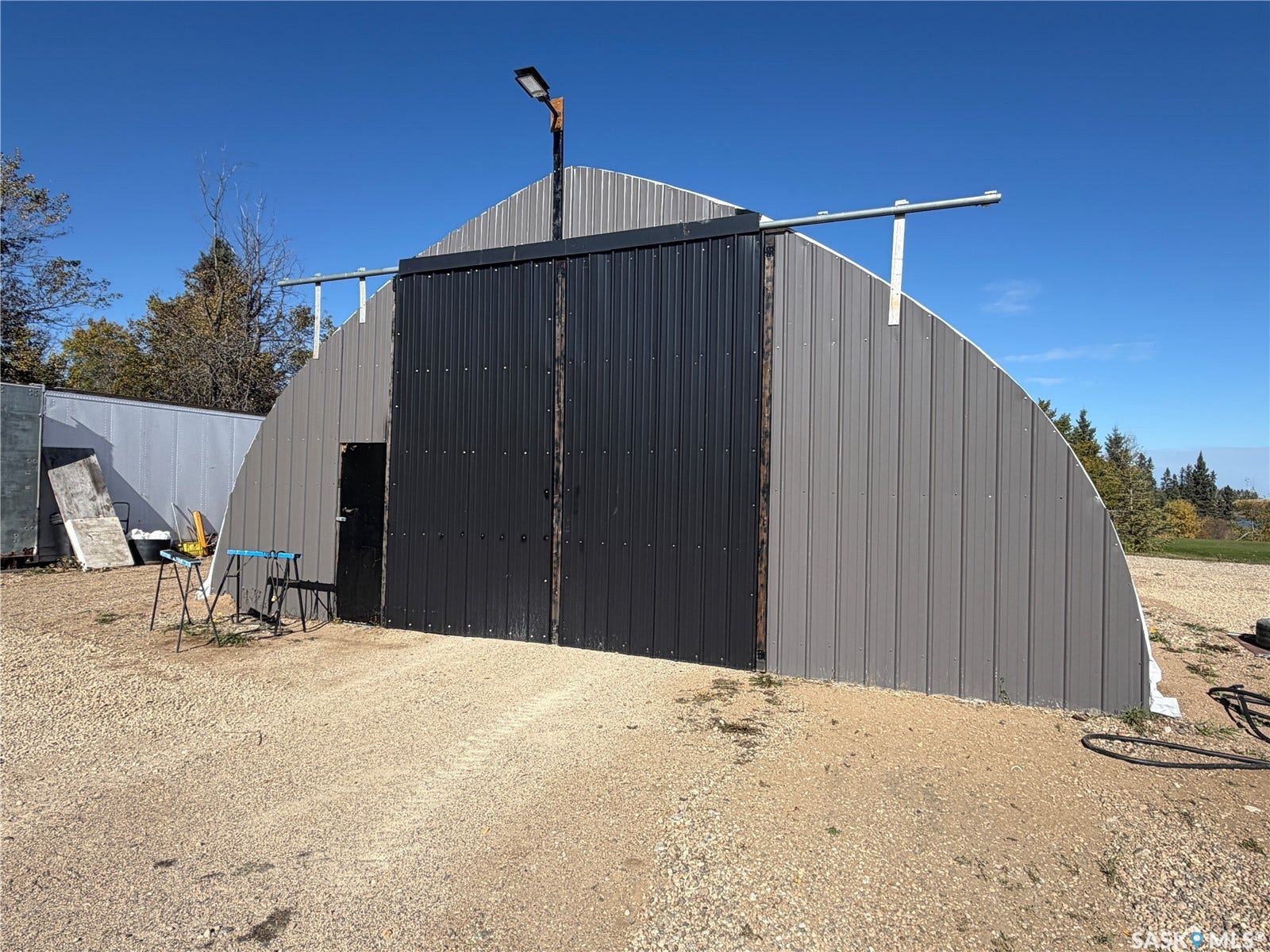 Quonset hut style structure with corrugated metal siding, sliding metal door, and exterior lighting fixture