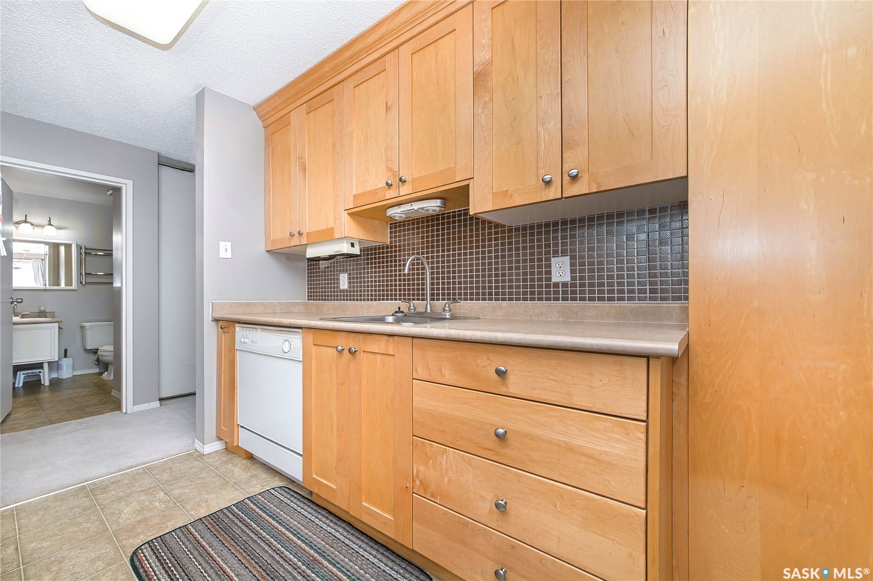 Kitchen featuring wood-finish cabinetry, integrated dishwasher, and tile backsplash