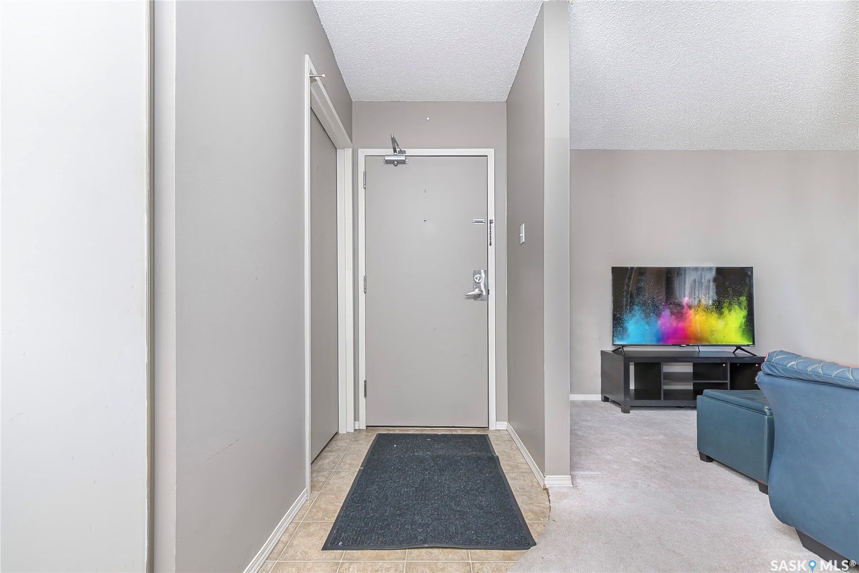 Entryway with neutral wall tones and tile flooring leading to carpeted living space