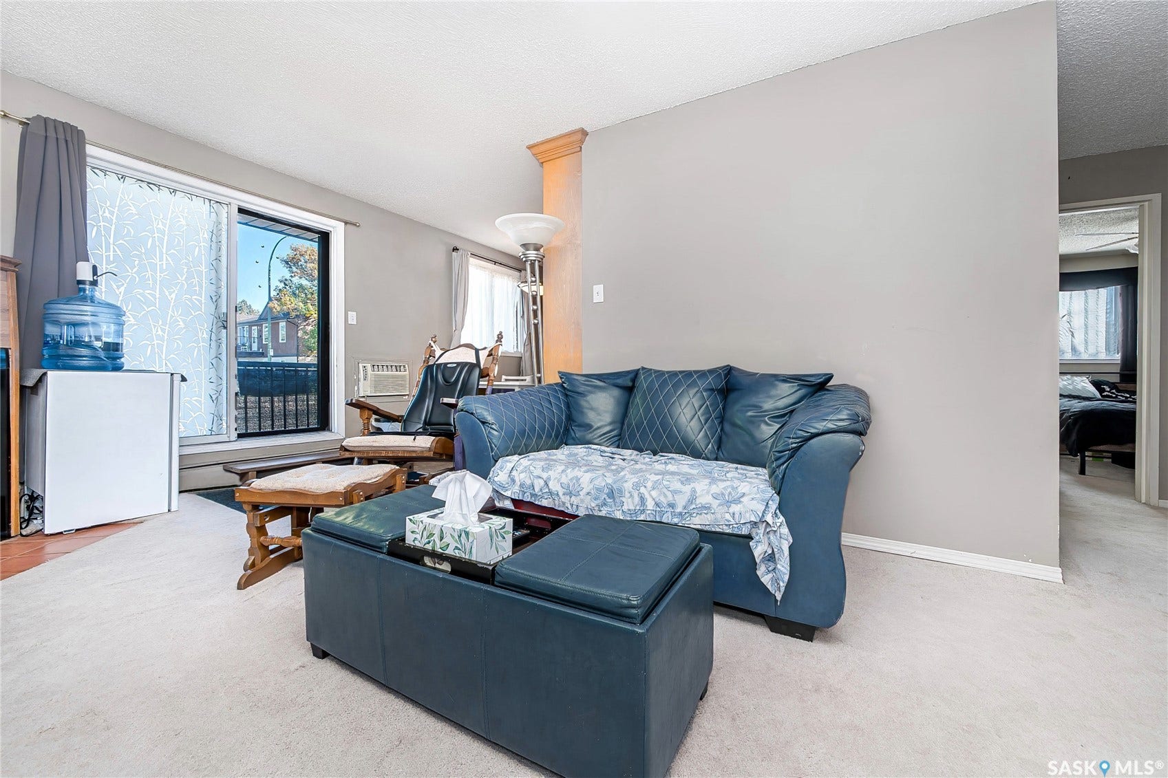 Neutral wall color, light-colored carpeting, sliding glass patio door, and a built-in architectural column