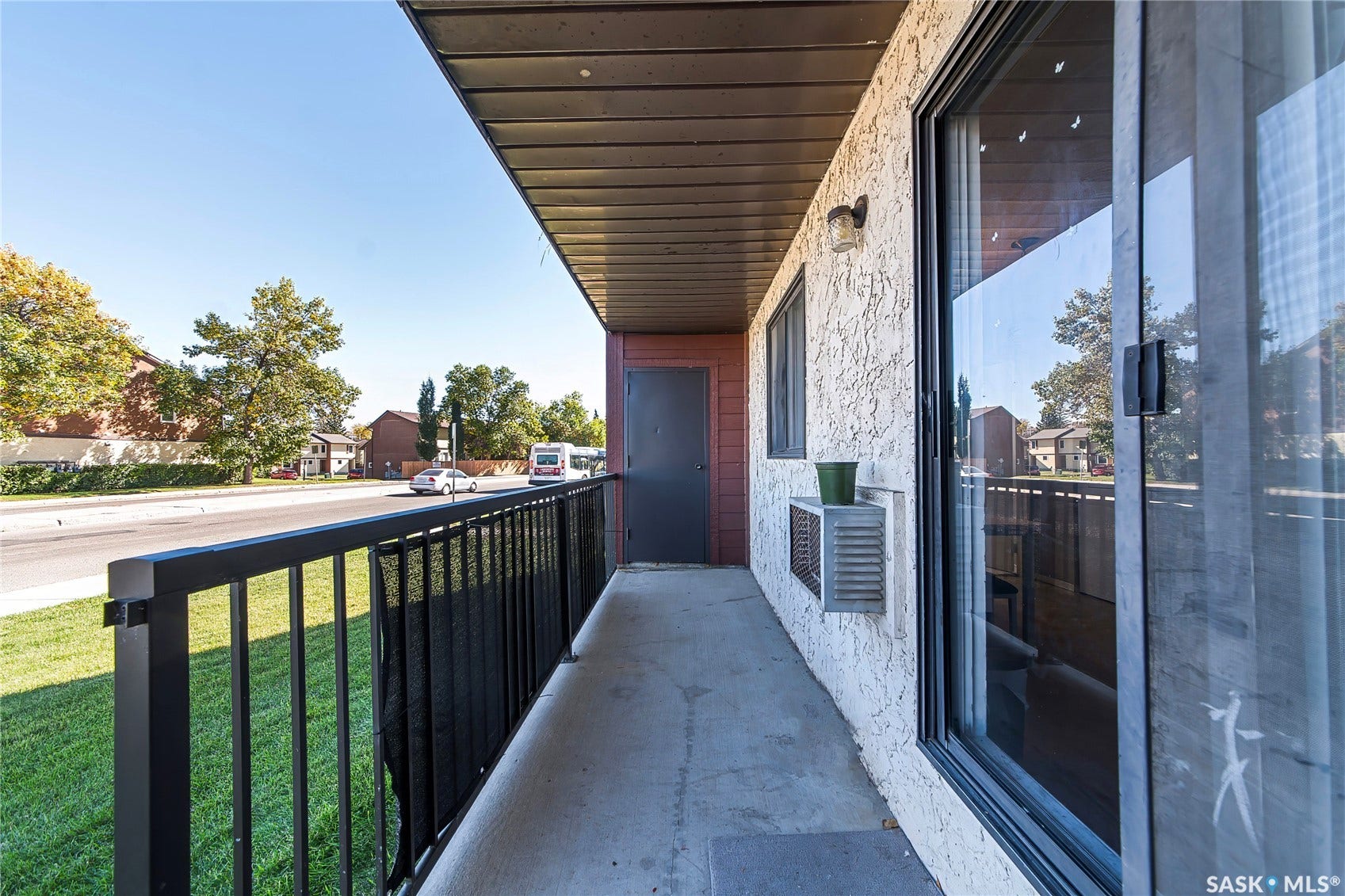 Private balcony with concrete flooring, black metal railing, and textured stucco exterior