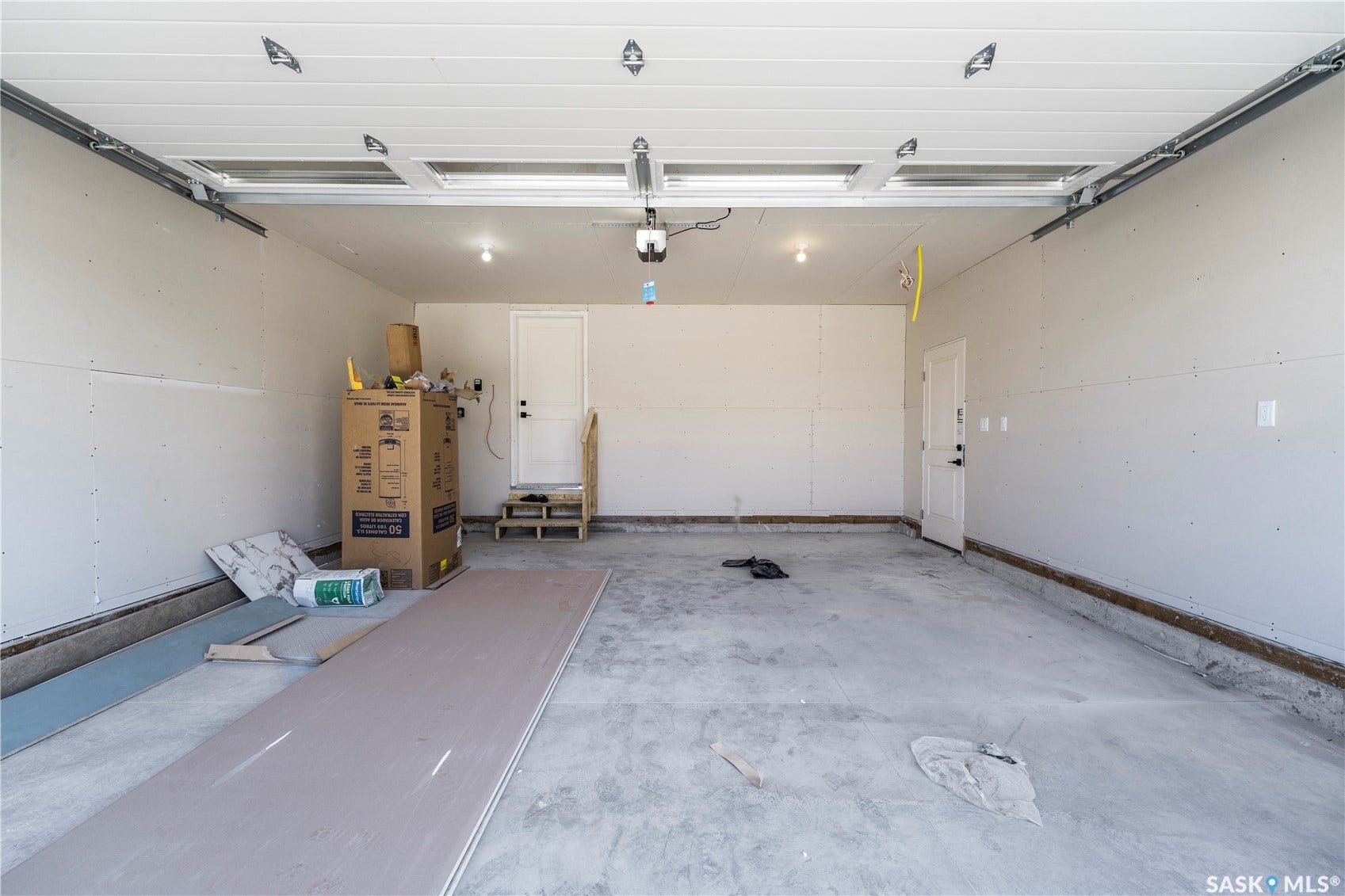 Spacious two-car garage with concrete flooring, automatic garage door, and recessed lighting