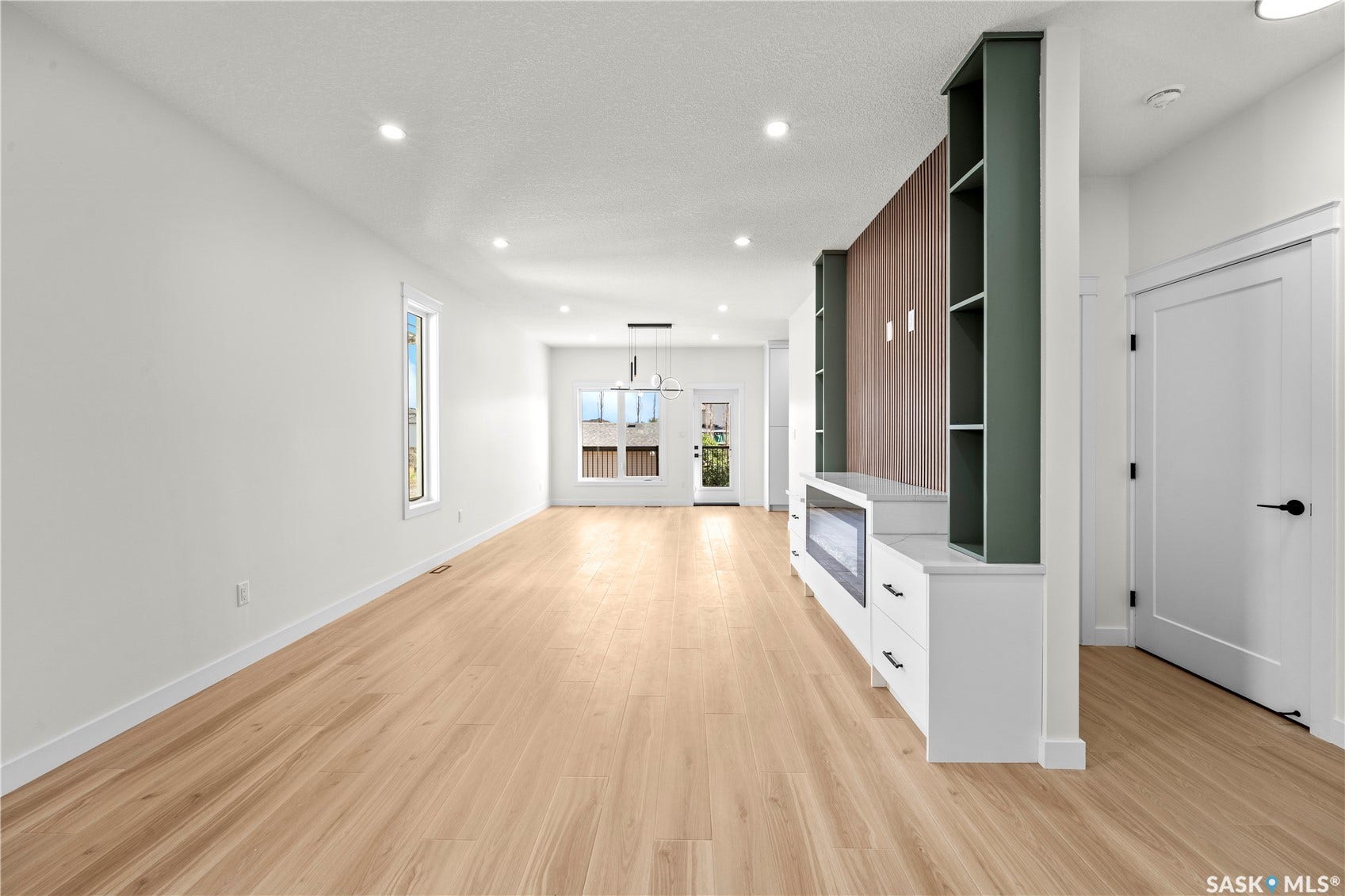 Spacious interior with wood-finish flooring, recessed lighting, and a built-in media console with shelving
