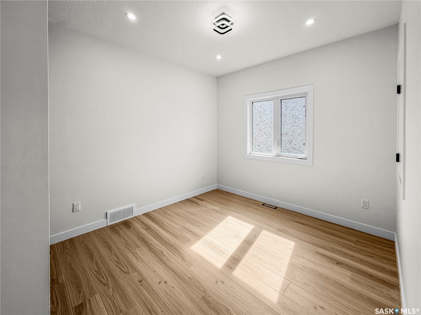 Wood-finish flooring with white baseboards, recessed ceiling lighting, and a modern ceiling fixture