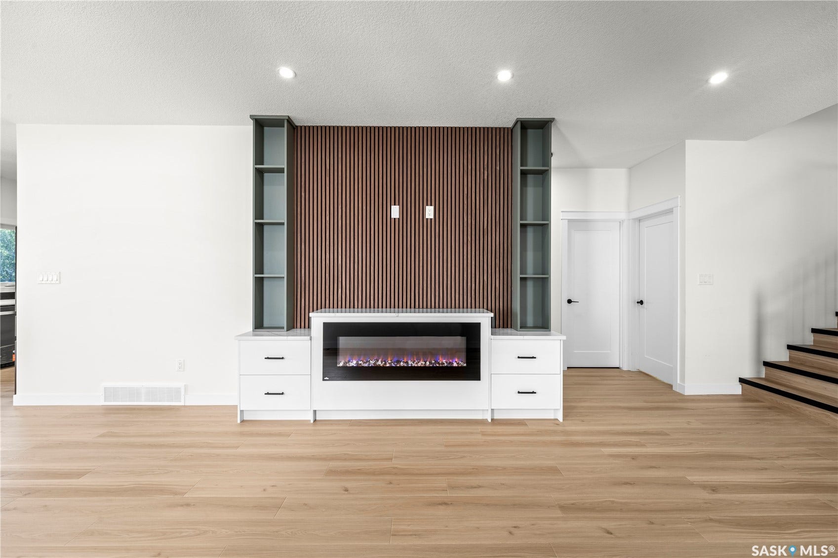 Built-in media console with storage, electric fireplace, wood-finish accent wall, recessed lighting, and light wood-finish flooring