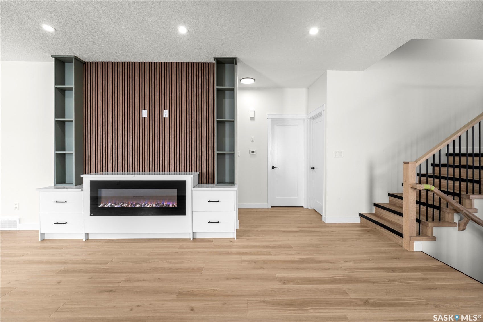 Wood-finish flooring throughout, featuring a built-in media center with an electric fireplace, integrated shelving, and a wood-slat accent wall